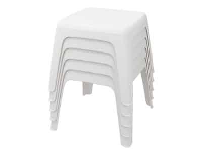 Imagen de pila de unas mesas pequeñas de plástico color blanco con cuatro patas y tablero plano sin respaldo.