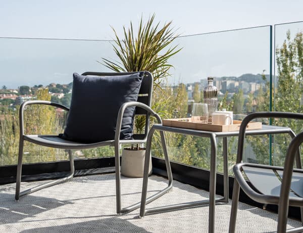 Se observa un par de sillas de aluminio junto a una mesa en una terraza