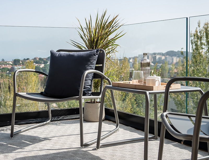 Se observa un par de sillas de aluminio junto a una mesa en una terraza