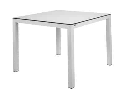The image shows a square table with a simple and modern design, with a white surface with HPL top and four legs made of aluminum. The style is minimalist and elegant.