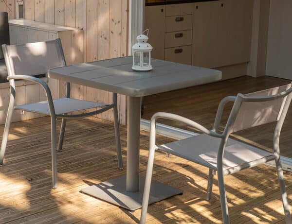 Se observan dos sillas grises junto a una mesa gris en el exterior