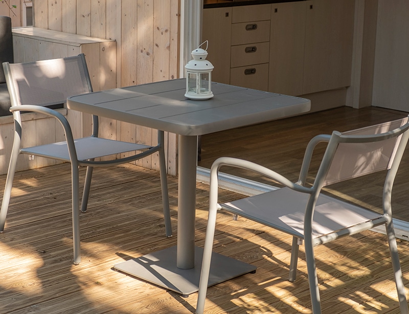 Se observan dos sillas grises junto a una mesa gris en el exterior