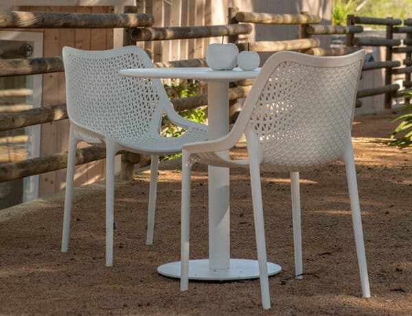 Two white chairs are seen next to a white table outside